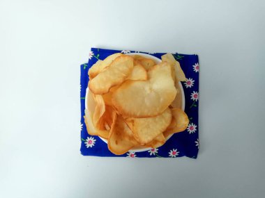 Tapyoka cipsi, ya da manyok cipsi, ya da kızartılmış manyok kökü. Mavi peçeteli beyaz bir kasede. Beyaz arkaplanda izole edilmiş