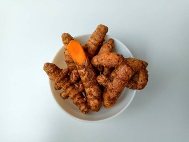 Beyaz arka planda izole edilmiş bir kasede zerdeçal ya da Curcuma longa rizomları