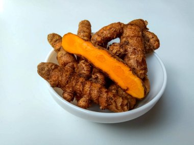 Beyaz arka planda izole edilmiş bir kasede zerdeçal ya da Curcuma longa rizomları