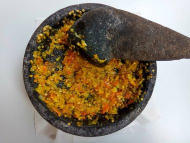 Endonezya 'dan gelen Sambal ya da geleneksel biber sosu. Taş havan ve tokmak kullanılarak yeni yapılmış, beyaz arka planda izole edilmiş.