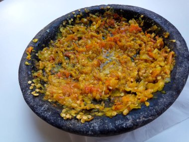 Endonezya 'dan gelen Sambal ya da geleneksel biber sosu. Taş havan ve tokmak kullanılarak yeni yapılmış, beyaz arka planda izole edilmiş.