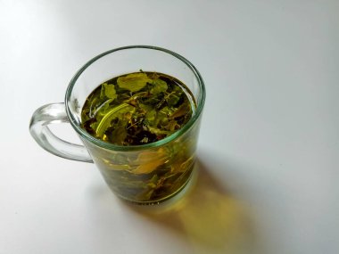 Moringa oleifera bitkisel çay gibi, şeffaf cam içinde, beyaz arka planda izole.