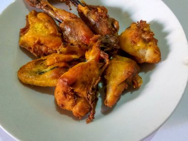 Zerdeçal ile tatlandırılmış kızarmış tavuklar, böylece sararır, beyaz tabakta, beyaz arka planda izole olur.