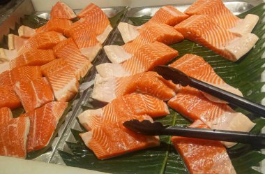 Taze somon ya da çiğ balık filetosu bir markette yaprak tabanında toplanmaya hazır.