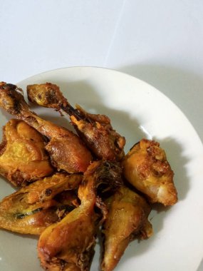 Zerdeçal ile tatlandırılmış kızarmış tavuklar, böylece sararır, beyaz tabakta, beyaz arka planda izole olur.