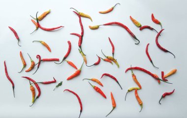 Arka arkaya küçük kırmızı biber kağıtları, turuncu gölgeler. Sarı ahşap yüzeyin üstünde