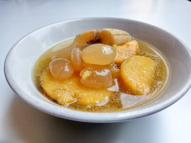 Kolak ya da Endonezya tatlısı, muz, palmiye tohumu ve tatlı patateslerden yapılmış, beyaz bir kasenin içinde.