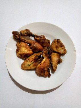 Bazı kızarmış tavuklar zerdeçal ile çeşnilendirilir, böylece sararır, beyaz tabakta, beyaz arka planda izole olur.