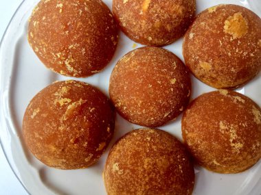 Gula jawa ya da java şekeri ya da kırmızı şeker ya da palmiye şekeri, yarım top şeklinde, beyaz kasenin içinde. Beyaz arkaplanda izole edilmiş