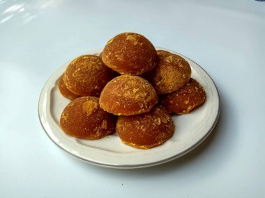 Gula jawa ya da java şekeri ya da kırmızı şeker ya da palmiye şekeri, yarım top şeklinde, beyaz kasenin içinde. Beyaz arkaplanda izole edilmiş