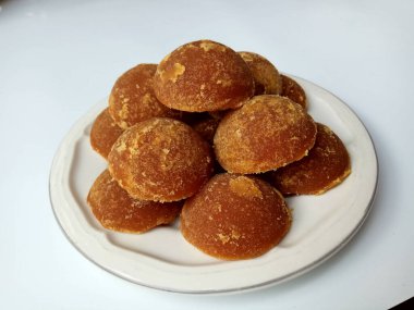 Gula jawa ya da java şekeri ya da kırmızı şeker ya da palmiye şekeri, yarım top şeklinde, beyaz kasenin içinde. Beyaz arkaplanda izole edilmiş
