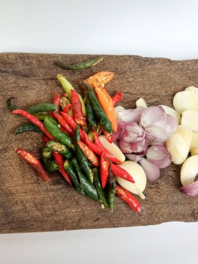 Tahta kesim tahtasında dilimlenmiş soğan, sarımsak ve biber, beyaz arka planda izole edilmiş.