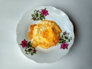 Tabakta sahanda yumurta. Biraz fazla pişmiş ve çıtır çıtır, çok yağlı kızartılmış.