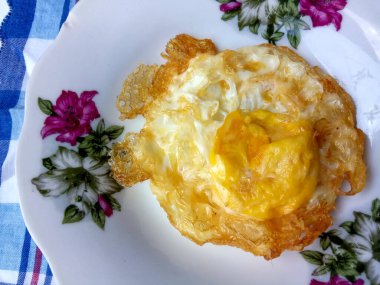 Tabakta sahanda yumurta. Biraz fazla pişmiş ve çıtır çıtır, çok yağlı kızartılmış.