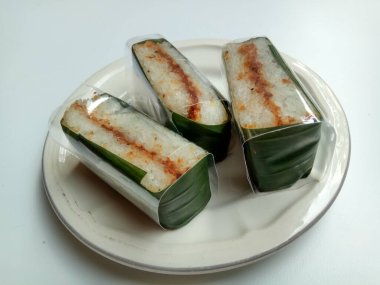 Lemper ayam, muz yaprağı ve şeffaf plastiğe sarılmış glutinöz pirinçten yapılmış bir Endonezya çerezi. Beyaz arkaplanda izole.