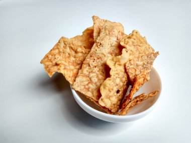 Keripik tempo ya da tempeh krakerleri. Beyaz arka planda izole edilmiş beyaz bir kasenin içinde.