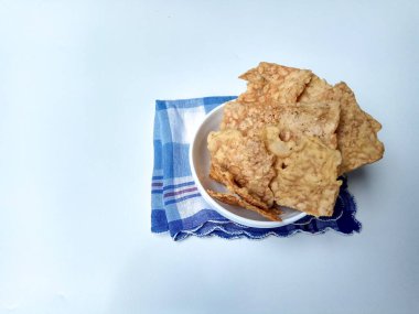 Keripik tempo ya da tempeh krakerleri. Beyaz arka planda izole edilmiş beyaz bir kasenin içinde.