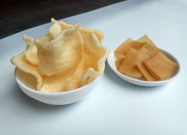 Kerupuk terigu ya da un krakerleri. Kızarmadan önce ve sonra. Endonezya yemeği ya da atıştırmalık olarak. Beyaz bir kasenin içine yerleştirilmiş..