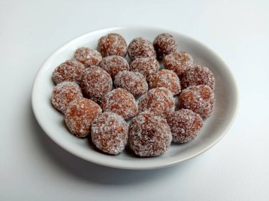 Demirhindi şekeri, beyaz küçük tabağın içine yerleştirilmiş. Demirhindi ezmesinden yapılmış ve şekerle kaplanmış tatlı ve ekşi şeker..