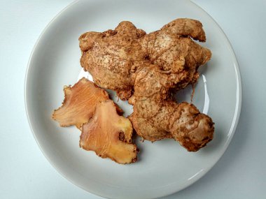 Zingiber officinale rhizome ya da toprak kaplı zencefil kökü, küçük beyaz tabakta. Beyaz arkaplanda izole edilmiş.