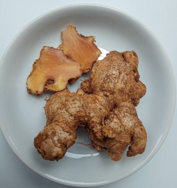 Zingiber officinale rhizome ya da toprak kaplı zencefil kökü, küçük beyaz tabakta. Beyaz arkaplanda izole edilmiş.