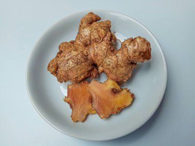 Zingiber officinale rhizome ya da toprak kaplı zencefil kökü, küçük beyaz tabakta. Beyaz arkaplanda izole edilmiş.