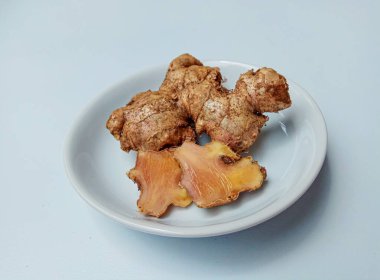 Zingiber officinale rhizome ya da toprak kaplı zencefil kökü, küçük beyaz tabakta. Beyaz arkaplanda izole edilmiş.