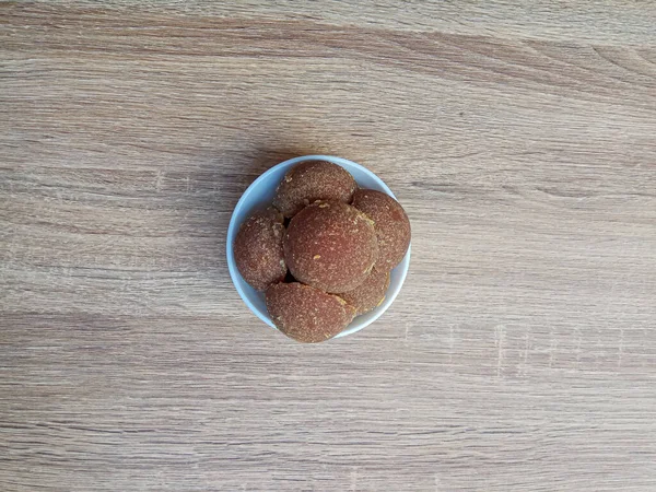 Gula jawa ya da java şekeri ya da kırmızı şeker ya da palmiye şekeri, yarım top şeklinde, beyaz kasenin içinde.