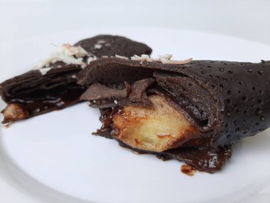 Dadar Gulung Pisang Cokelat, ya da muz ve çikolata soslu rulo tatlı omlet. Endonezya 'dan geleneksel atıştırmalıklar. Beyaz arkaplanda izole edilmiş.