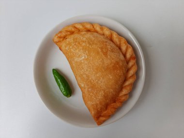 Pastel, tavuk eti ve karışık sebzelerle dolu bir hamur işi, sonra da bol yağda kızartılmış. Endonezya 'dan atıştırmalık. Beyaz tabakta. Beyaz arkaplanda izole edilmiş.