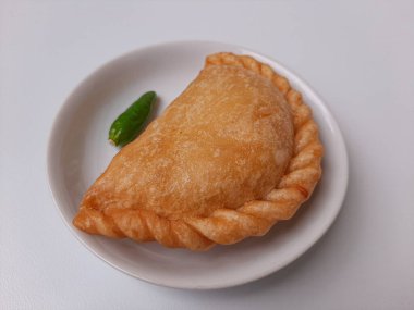 Pastel, tavuk eti ve karışık sebzelerle dolu bir hamur işi, sonra da bol yağda kızartılmış. Endonezya 'dan atıştırmalık. Beyaz tabakta. Beyaz arkaplanda izole edilmiş.