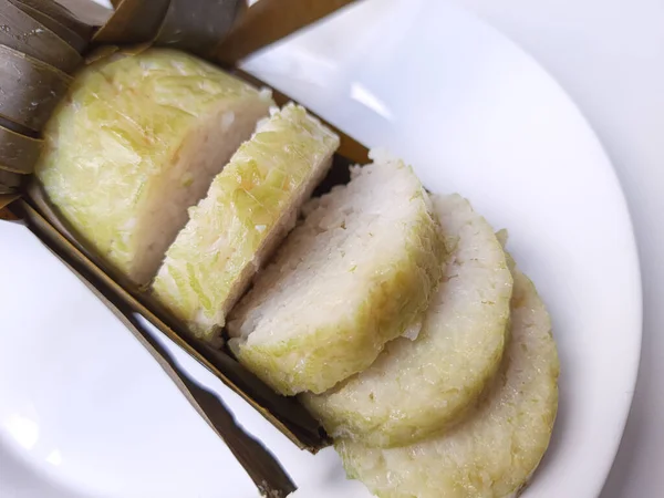 Lontong is an Indonesian dish made of compressed rice cake in the form of a cylinder wrapped inside a banana leaf. Cut into slices. Isolated in white background.