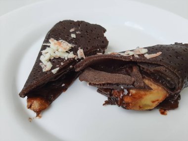 Dadar Gulung Pisang Cokelat, ya da muz ve çikolata soslu rulo tatlı omlet. Endonezya 'dan geleneksel atıştırmalıklar. Beyaz arka planda izole edilmiş. Üst görünüm veya düz uzanma