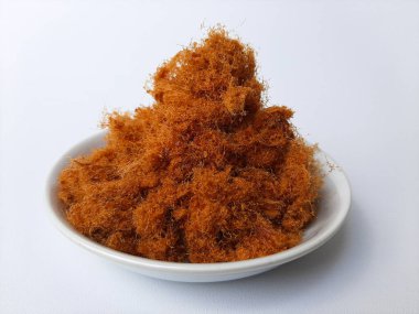 Tavuk diş ipi, yumuşak ve yumuşak dokusu kalın pamuğa benzeyen kurutulmuş et ürünüdür. Küçük bir tabakta, beyaz arka planda izole edilmiş.