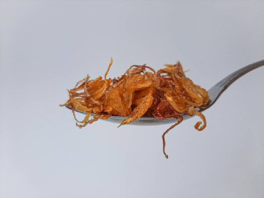 Metal kaşıkta kızarmış soğan yığını. Beyaz arkaplanda izole edilmiş.