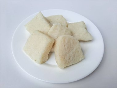 Jadah ketan, Endonezya 'dan geleneksel bir aperatif. Yapışkan pirinç ve rendelenmiş hindistan cevizinden yapılmış. Genellikle çay saatinde atıştırmalık olarak servis edilir. Beyaz bir plaka üzerinde, beyaz arka planda izole edilmiş.