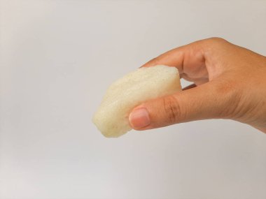 Jadah ketan, Endonezya 'dan geleneksel bir aperatif. Yapışkan pirinç ve rendelenmiş hindistan cevizinden yapılmış. Beyaz arka planda izole edilmiş. Yan görüş. Elinle tut.