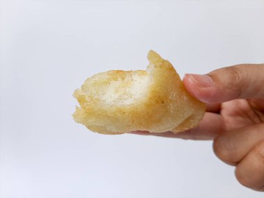 Kızarmış jadah ketan, Endonezya 'dan geleneksel bir aperatiftir. Yapışkan pirinç ve rendelenmiş hindistan cevizinden yapılmış. Beyaz arka planda izole edilmiş. Elinle tut. Yan görüş. Isırık