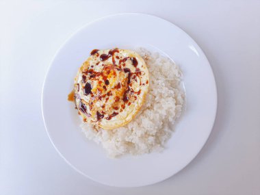 Beyaz arka planda izole edilmiş beyaz bir tabakta beyaz pirinç ve soya sosuyla servis edilen kızarmış yumurta ya da güneşli tarafı. Metin için boşluk