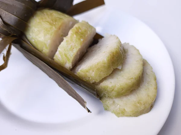 Lontong is an Indonesian dish made of compressed rice cake in the form of a cylinder wrapped inside a banana leaf. Cut into slices. Isolated in white background.