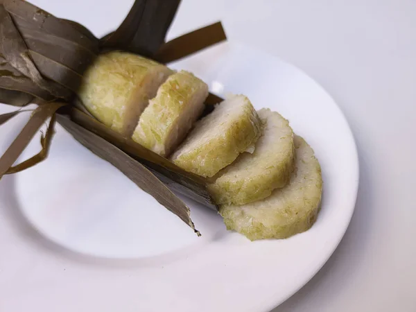 Lontong is an Indonesian dish made of compressed rice cake in the form of a cylinder wrapped inside a banana leaf. Cut into slices. Isolated in white background.