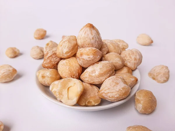 stock image Aleurites moluccanus or Indonesian Candlenuts called Kemiri, inside a smale plate, isolated in white background