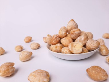 Aleurite moluccanus veya Kemiri adı verilen Endonezya Candlenuts, beyaz arka planda izole edilmiş bir smale plakasının içinde.