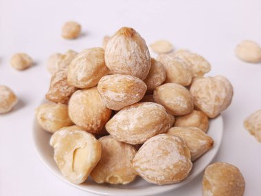 Aleurite moluccanus veya Kemiri adı verilen Endonezya Candlenuts, beyaz arka planda izole edilmiş bir smale plakasının içinde.