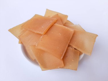 Çiğ Kerupuk terigu, ya da un krakeri, kızarmadan önce. Kare şeklinde. Endonezya yemeği ya da atıştırmalık olarak. Beyaz bir plakanın içine yerleştirilmiş, beyaz arka planda izole edilmiş.