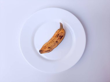 Beyaz bir tabakta muz buğulama. Beyaz arkaplanda izole edilmiş