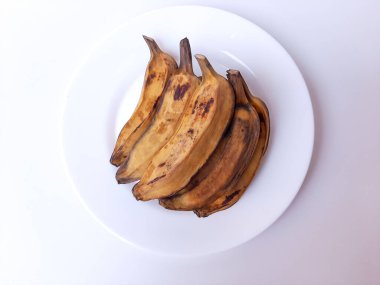 Beyaz bir tabakta muz buğulama. Beyaz arkaplanda izole edilmiş