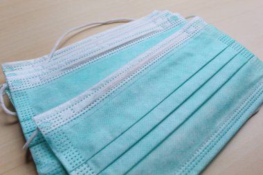 Bazı tıbbi ya da cerrahi maske parçaları, sarı ahşap yüzeyde.