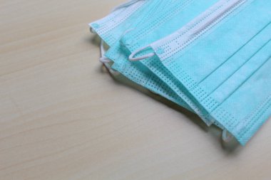 Bazı tıbbi ya da cerrahi maske parçaları, sarı ahşap yüzeyde.