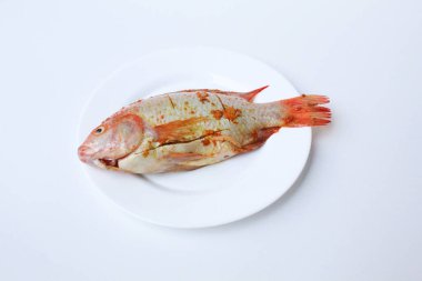 Red Nile Tilapia, Red Tilapia, veya Oreochromis niloticus. Ezilmiş zerdeçal ile tatlandırılmış taze balık. Beyaz arka planda izole edilmiş pembe kasenin içinde.